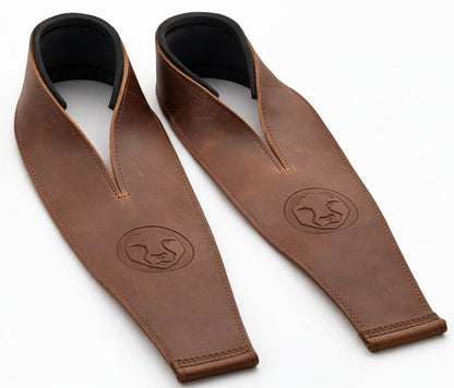 Two brown leather weightlifting straps with black neoprene wrist support on a white background